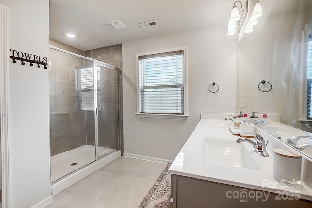 bathroom with double vanity, baseboards, visible vents, a shower stall, and a sink