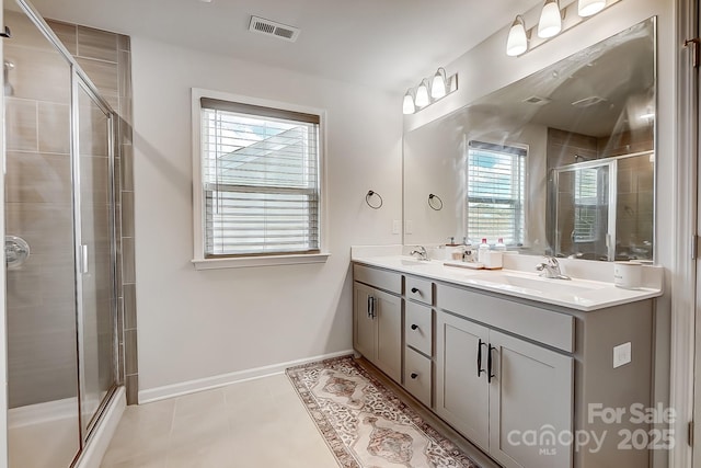 bathroom with double vanity, a stall shower, a sink, and visible vents