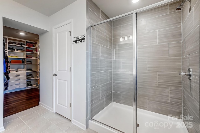 bathroom featuring a shower stall, a walk in closet, and tile patterned flooring