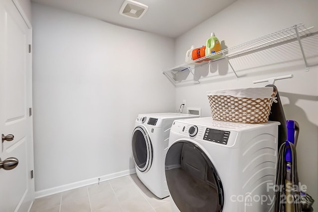 laundry room with laundry area, light tile patterned floors, baseboards, and washer and dryer