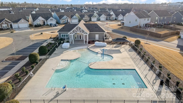 community pool with a patio, fence, and a residential view