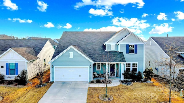 view of front of house with roof with shingles, board and batten siding, a front yard, a garage, and driveway