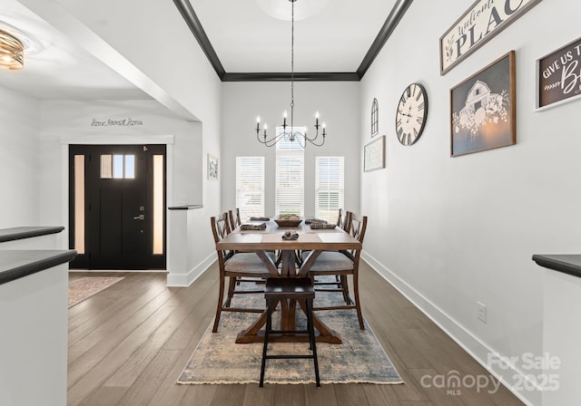 dining area featuring ornamental molding, dark wood-type flooring, and a chandelier