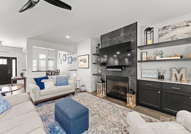 living room with ceiling fan with notable chandelier, a fireplace, and light hardwood / wood-style floors