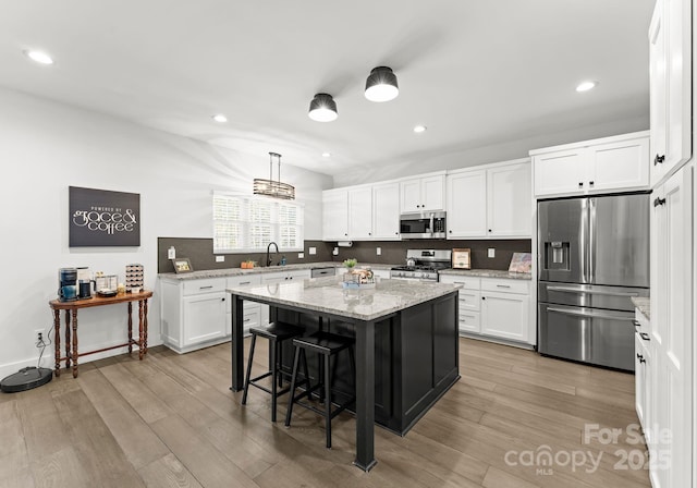 kitchen with white cabinetry, a kitchen island, a kitchen breakfast bar, and appliances with stainless steel finishes