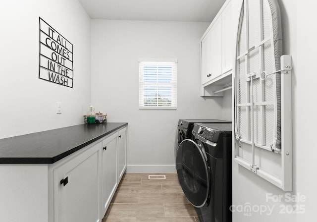 laundry area featuring cabinets, light wood-type flooring, and washer and clothes dryer