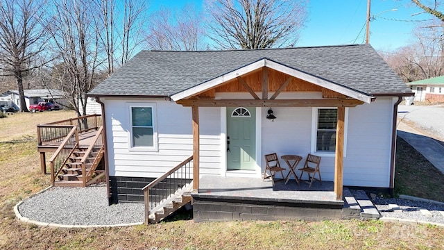 bungalow-style home featuring roof with shingles and stairs