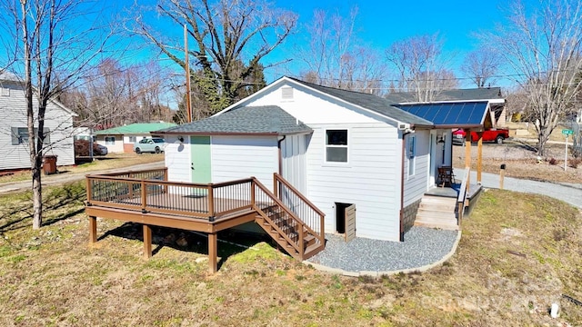 rear view of house with roof with shingles, stairway, a deck, and a yard