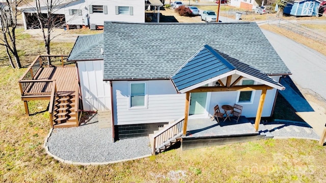 back of property with a shingled roof, stairway, and a wooden deck