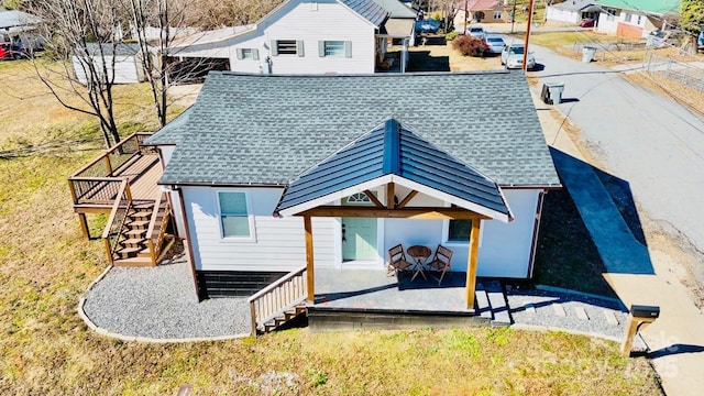 rear view of house with a patio area, roof with shingles, and stairs