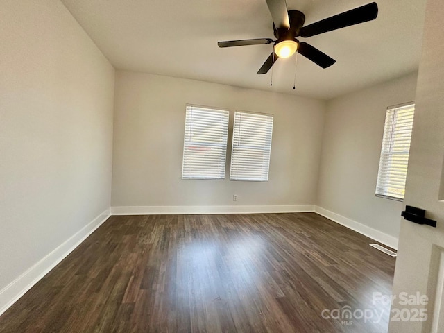 unfurnished room featuring dark wood-style flooring, visible vents, ceiling fan, and baseboards