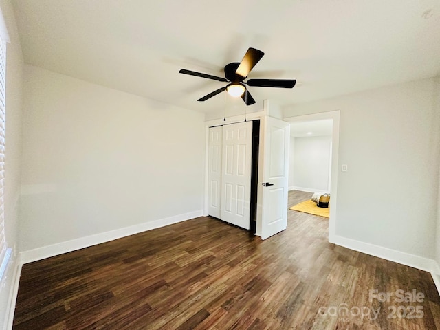 unfurnished bedroom featuring a closet, dark wood-style flooring, baseboards, and a ceiling fan