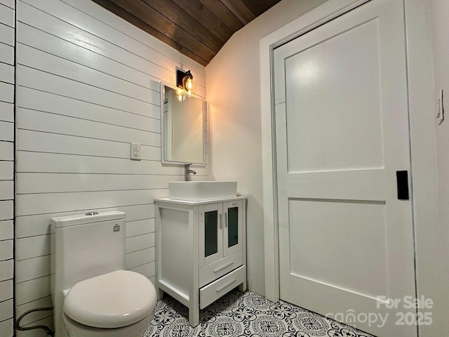 bathroom with toilet, wooden walls, vanity, tile patterned flooring, and wooden ceiling