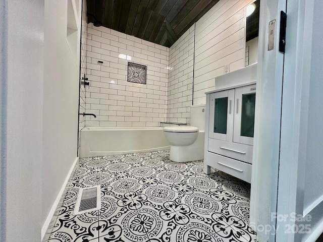 bathroom with toilet, tile patterned flooring, washtub / shower combination, and baseboards