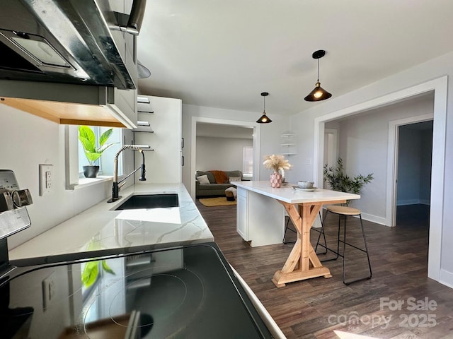 kitchen featuring dark wood-style flooring, a sink, decorative light fixtures, and light stone countertops