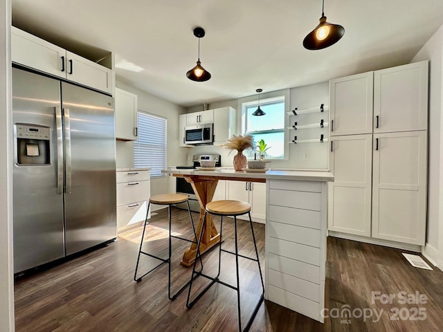 kitchen featuring hanging light fixtures, white cabinetry, appliances with stainless steel finishes, and light countertops