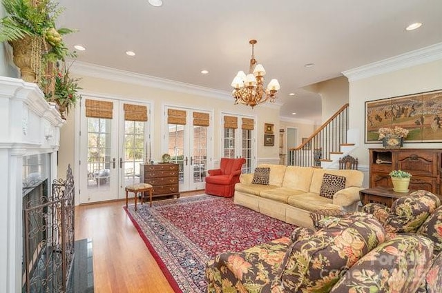 living room with an inviting chandelier, wood-type flooring, ornamental molding, and french doors