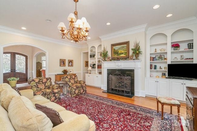 living room with ornamental molding, built in features, french doors, and light wood-type flooring