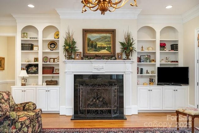 living room featuring ornamental molding, a chandelier, light hardwood / wood-style floors, and built in features