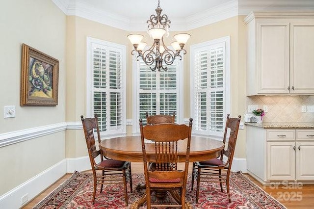 dining room with ornamental molding, light hardwood / wood-style flooring, and a notable chandelier