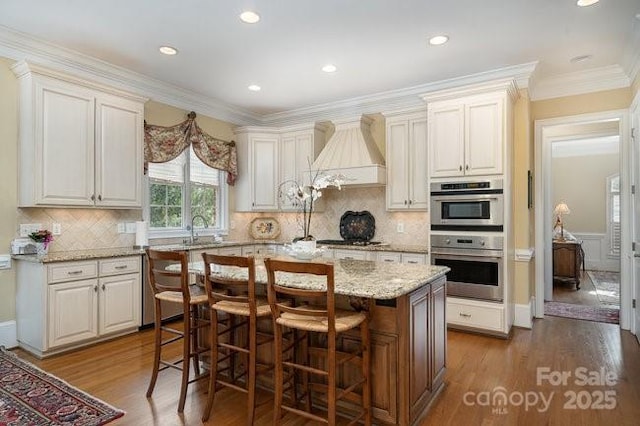 kitchen with premium range hood, light stone counters, a kitchen island, dark hardwood / wood-style flooring, and stainless steel double oven