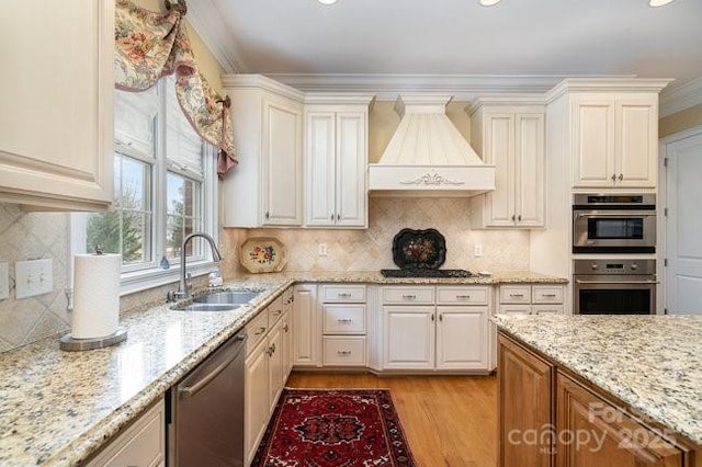 kitchen with sink, crown molding, light hardwood / wood-style flooring, appliances with stainless steel finishes, and light stone countertops