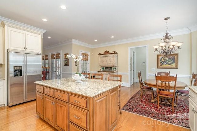 kitchen featuring pendant lighting, light hardwood / wood-style flooring, built in refrigerator, a center island, and ornamental molding