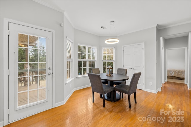 dining space with crown molding and light wood-type flooring