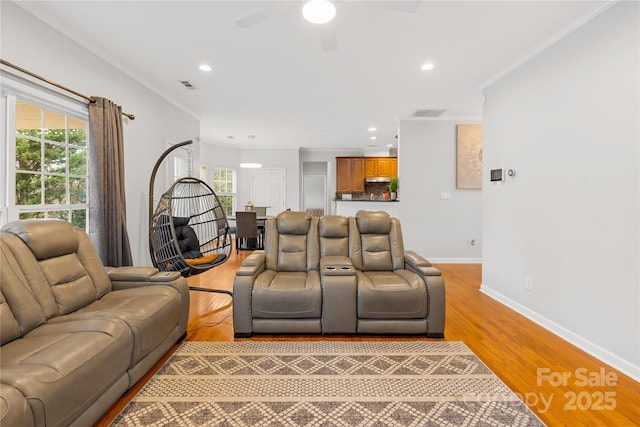 living room with ornamental molding, plenty of natural light, and light hardwood / wood-style flooring