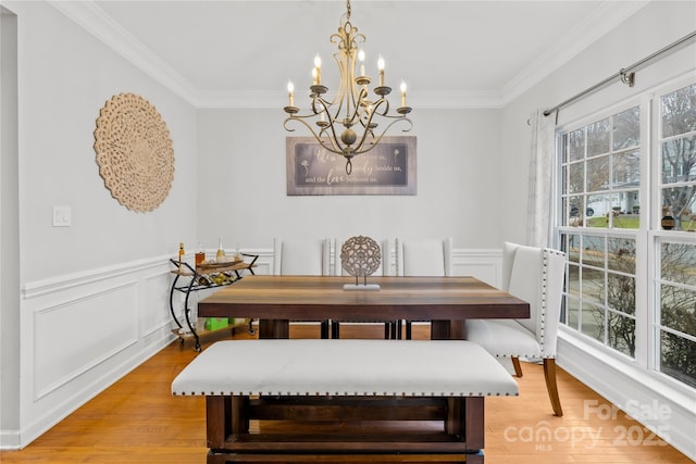 dining space featuring an inviting chandelier, ornamental molding, and light hardwood / wood-style floors