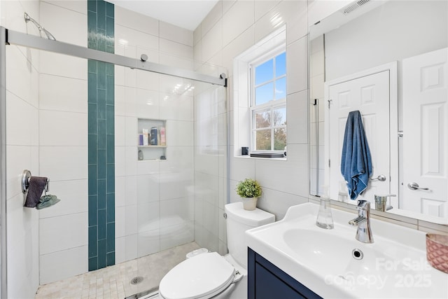 bathroom with vanity, tile walls, walk in shower, and toilet