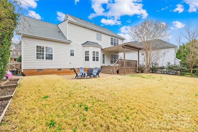 back of house featuring a wooden deck, a fire pit, a patio, and a yard