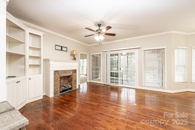 unfurnished living room featuring ornamental molding, a tile fireplace, dark hardwood / wood-style floors, and ceiling fan