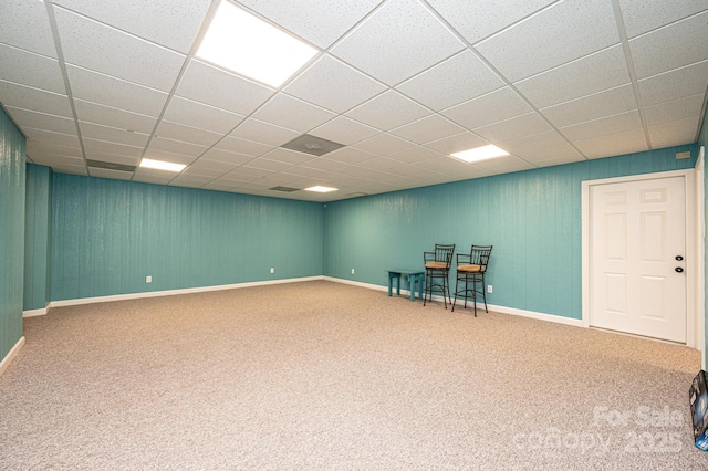 basement featuring a paneled ceiling and carpet flooring