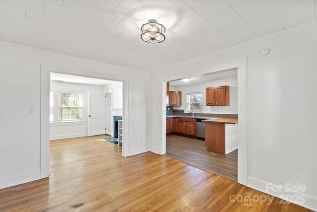 interior space featuring dishwasher, sink, ornamental molding, and light hardwood / wood-style flooring