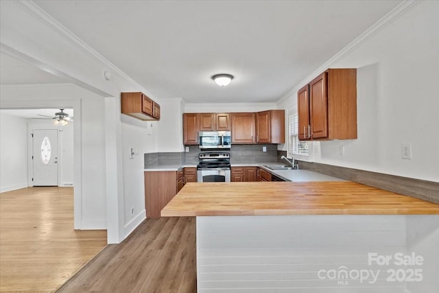 kitchen featuring crown molding, wooden counters, appliances with stainless steel finishes, kitchen peninsula, and light wood-type flooring