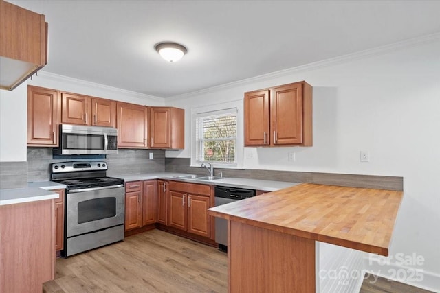 kitchen with sink, butcher block counters, stainless steel appliances, ornamental molding, and kitchen peninsula