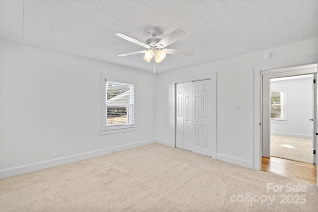 unfurnished bedroom featuring light colored carpet, ceiling fan, and a closet