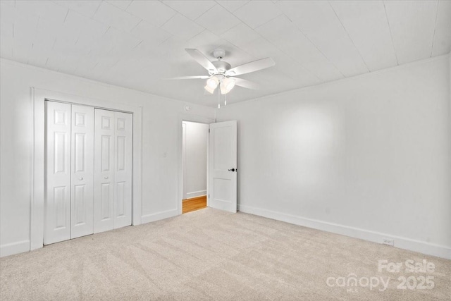 unfurnished bedroom with light carpet, ceiling fan, and a closet