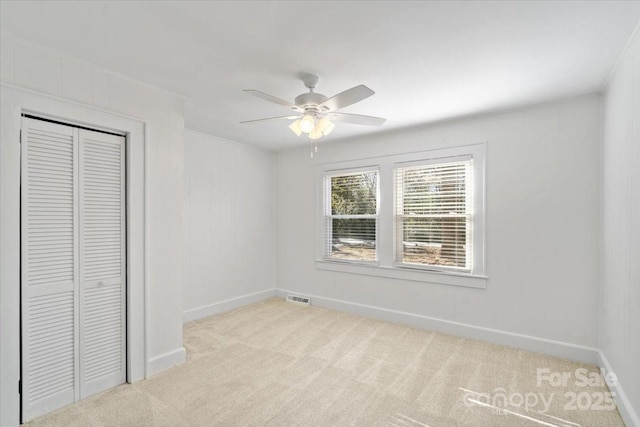 unfurnished bedroom featuring light carpet, ceiling fan, and a closet