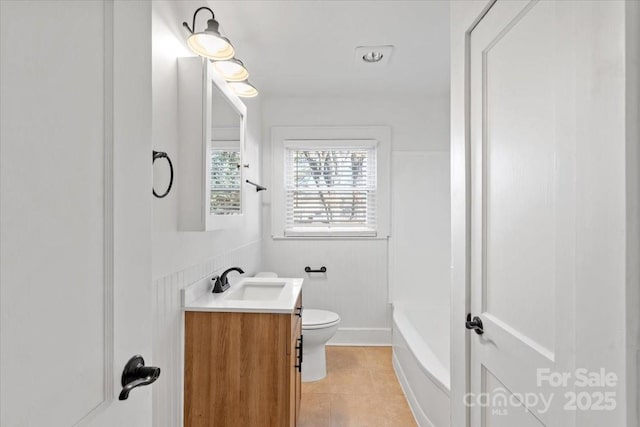 bathroom featuring vanity, a washtub, tile patterned floors, and toilet