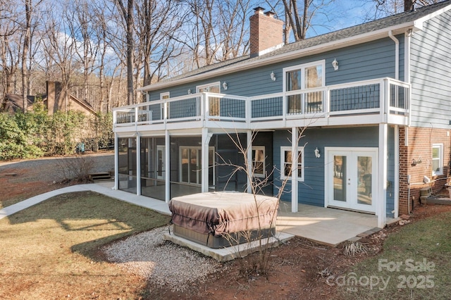 back of house with a yard, a hot tub, a sunroom, a patio area, and french doors