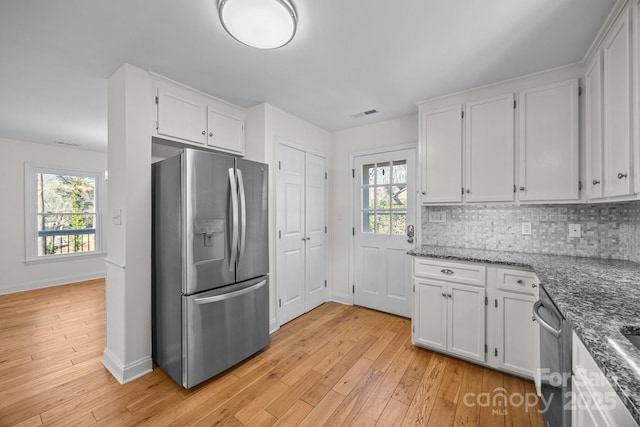 kitchen with stainless steel appliances, white cabinetry, decorative backsplash, and dark stone counters