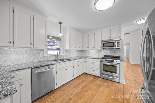 kitchen featuring stainless steel appliances, white cabinetry, hanging light fixtures, and sink