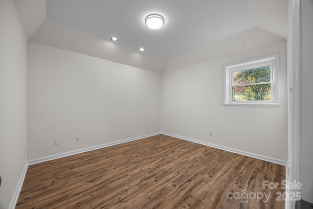 unfurnished room featuring dark wood-type flooring and lofted ceiling