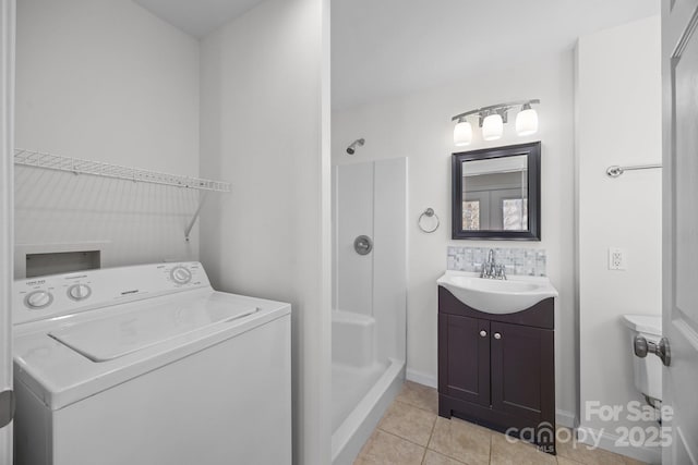 clothes washing area featuring sink, washer / dryer, and light tile patterned floors