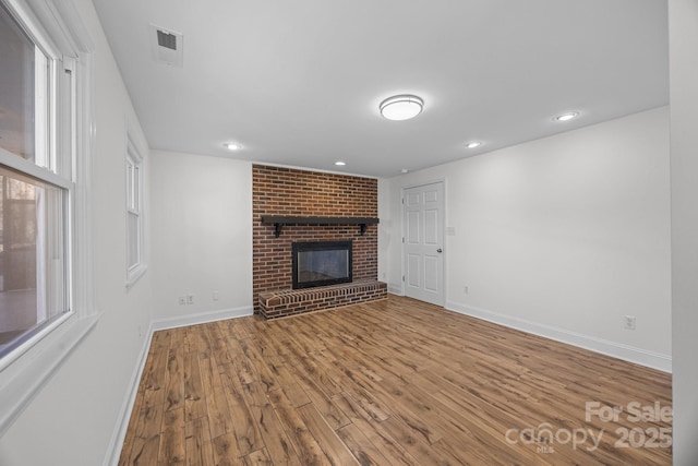 unfurnished living room with hardwood / wood-style floors, a fireplace, and plenty of natural light