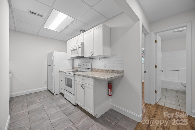 kitchen featuring white cabinetry, backsplash, white appliances, and a drop ceiling