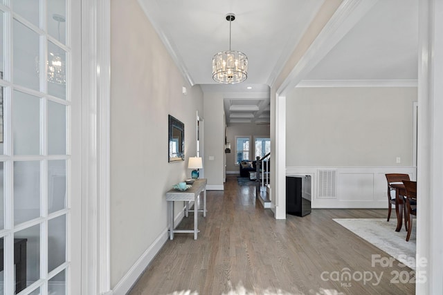 foyer with a notable chandelier, hardwood / wood-style flooring, ornamental molding, and beamed ceiling