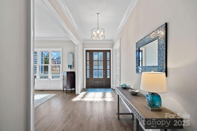 foyer entrance with an inviting chandelier, hardwood / wood-style flooring, plenty of natural light, and ornamental molding